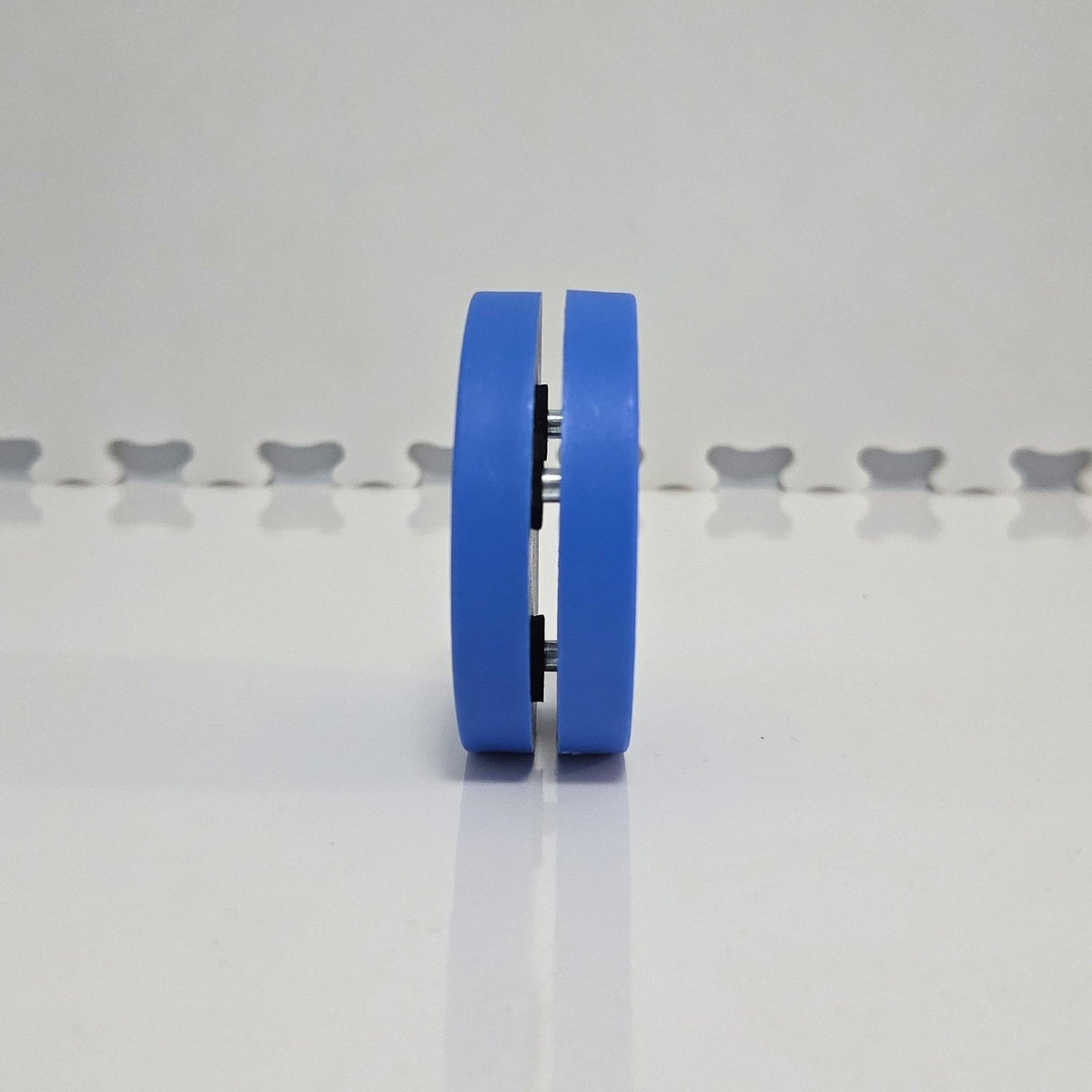 Direct side edge view of blue Everyday Ice off-ice training puck standing upright showing internal metal spacers and dual-plate construction